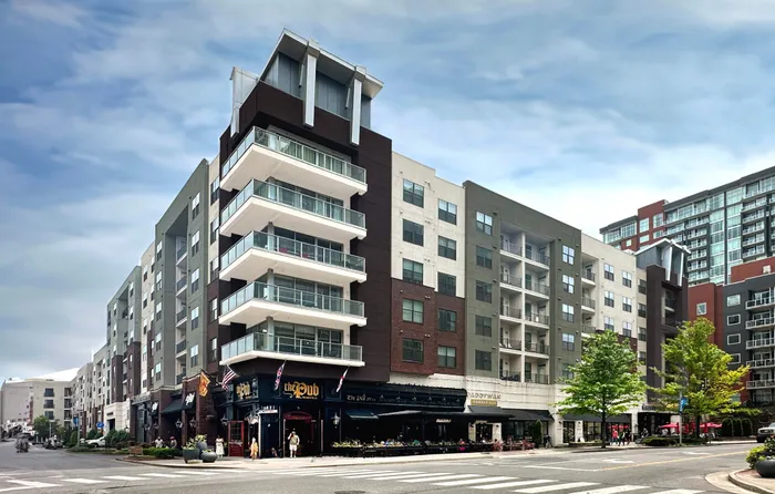 Contemporary urban apartment building showcasing modern architecture with spacious balconies and vibrant street-level shops.