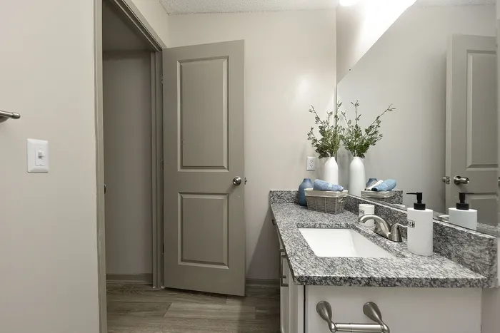 Modern bathroom featuring elegant granite countertop, sleek fixtures, and stylish decor with fresh towels.