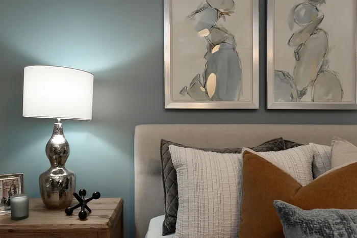 Elegant bedroom corner with soft lighting, stylish abstract art, and plush pillows creating a cozy atmosphere.