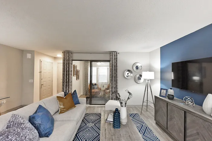 Chic living room featuring a plush sofa with vibrant cushions, elegant decor, and a modern entertainment center against a stylish blue accent wall.