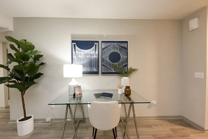 Inviting workspace featuring a chic glass desk, modern art, and vibrant indoor plant for a refreshing home office vibe.