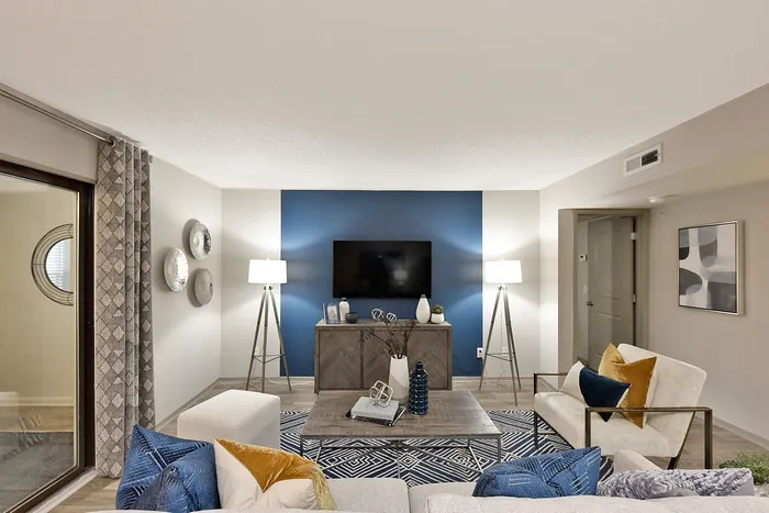 Inviting modern living room with elegant decor, featuring a sleek blue accent wall, cozy seating, stylish lamps, and a contemporary coffee table arrangement.
