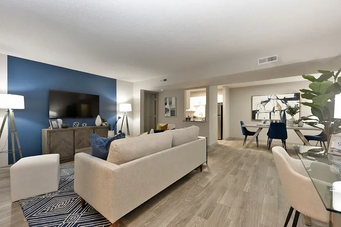 Modern open-concept living room with elegant decor, featuring a stylish blue accent wall and a cosy seating area.