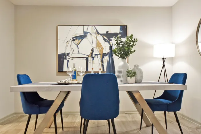 Elegant dining area featuring a modern table with vibrant blue chairs and abstract wall art, complemented by stylish decor and mood lighting.