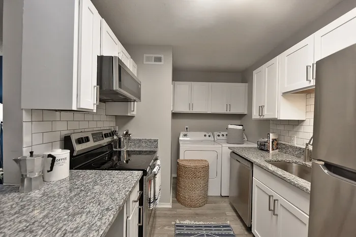 Modern kitchen with sleek granite countertops, stainless steel appliances, and in-unit laundry for convenient living.