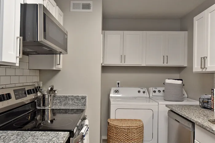 Modern kitchen featuring sleek granite countertops, stainless steel appliances, and convenient in-unit laundry facilities.
