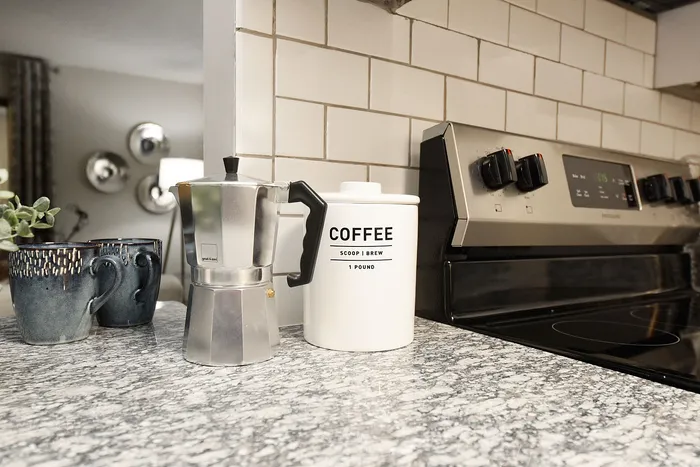 Cozy kitchen corner featuring a chic espresso maker, stylish coffee canister, and modern stovetop on speckled granite countertops.