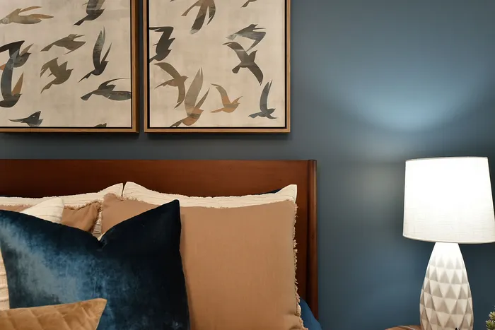 Elegant bedroom with sophisticated bird artwork, plush pillows, and ambient lighting for a cozy atmosphere.