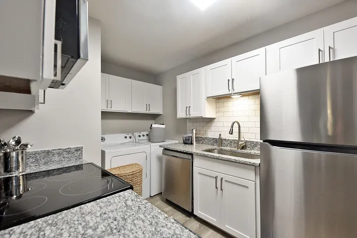 Modern kitchen featuring granite countertops, sleek stainless steel appliances, and elegant white cabinetry, offering a sophisticated cooking experience.