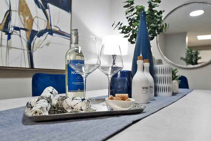 Elegant dining setup with a bottle of Sauvignon Blanc, wine glasses, and stylish decor on a chic table in a modern apartment.