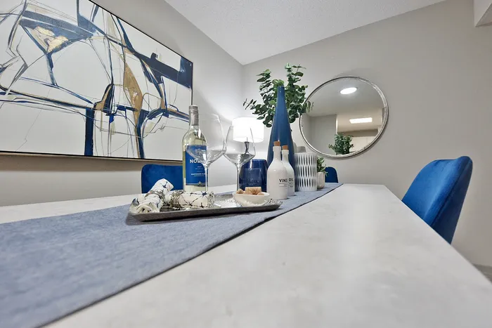 Elegant dining room setup with modern abstract art, stylish decor, and vibrant blue accents.