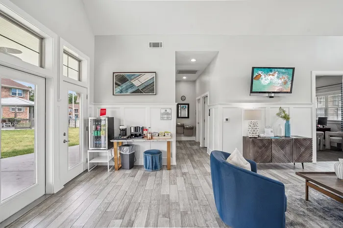 Contemporary apartment lobby with bright natural light, cozy seating, a refreshment station, and stylish decor.