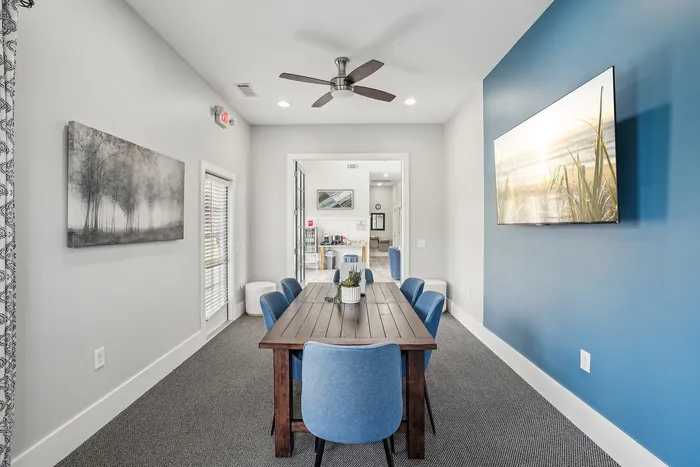 Inviting dining area with a rustic wooden table, vibrant blue chairs, and modern decor in a stylish apartment.