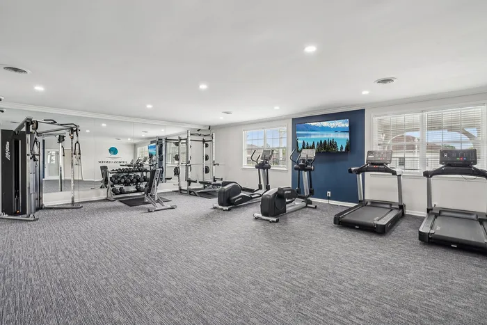 Modern fitness center featuring state-of-the-art exercise equipment, mirrored walls, and natural lighting.