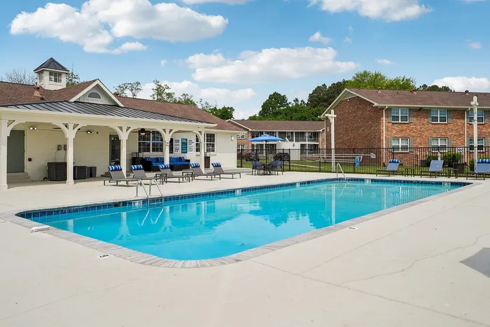 Inviting outdoor pool area with comfortable loungers and umbrellas, perfect for relaxation and leisure in a serene residential setting.