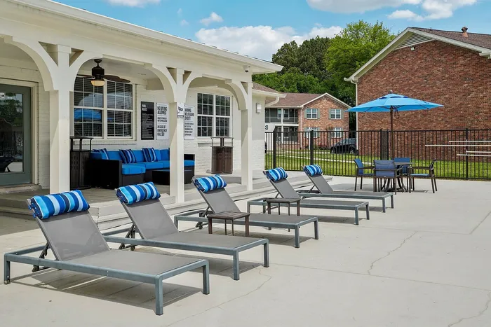 Inviting outdoor poolside area with stylish lounge chairs and vibrant blue accents, perfect for relaxation and social gatherings.