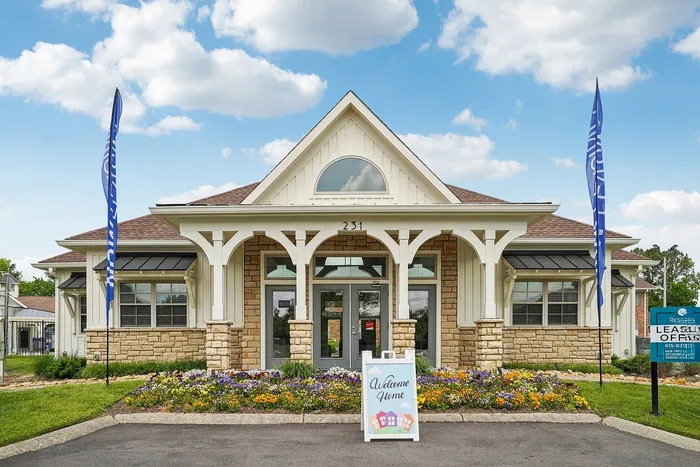 Charming leasing office with rustic stone facade and colorful flower beds, inviting you to find your perfect home.