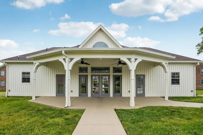 Charming white farmhouse-style exterior with spacious covered patio and manicured lawn, perfect for relaxation.