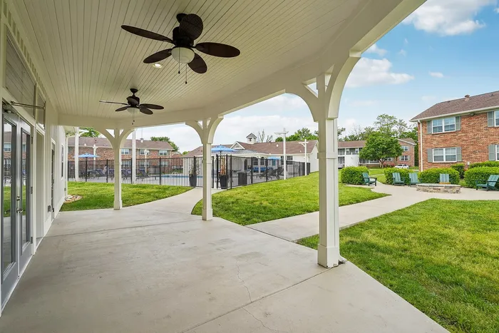 Spacious covered patio with modern ceiling fans overlooking a vibrant community courtyard and pristine swimming pool area.