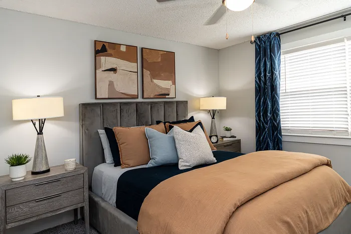 Inviting bedroom with elegant decor, featuring plush bedding, modern lamps, stylish artwork, and abundant natural light.