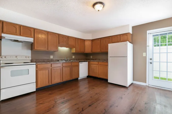 Beautiful kitchen with warm wooden cabinetry, modern appliances, and natural light from a glass patio door.