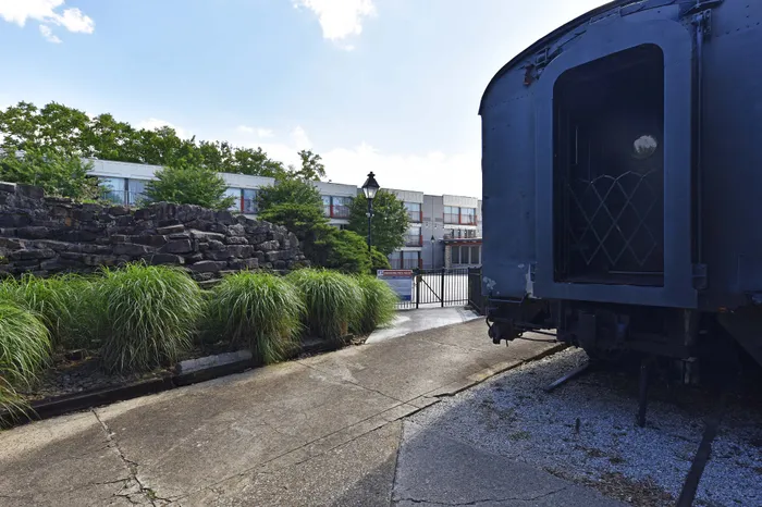 Charming courtyard view with lush greenery and a historic train carriage, offering unique character and appeal.