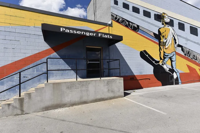 Vibrant mural on Passenger Flats featuring a colorful depiction of a traveler with a guitar, adding artistic flair to the entryway.