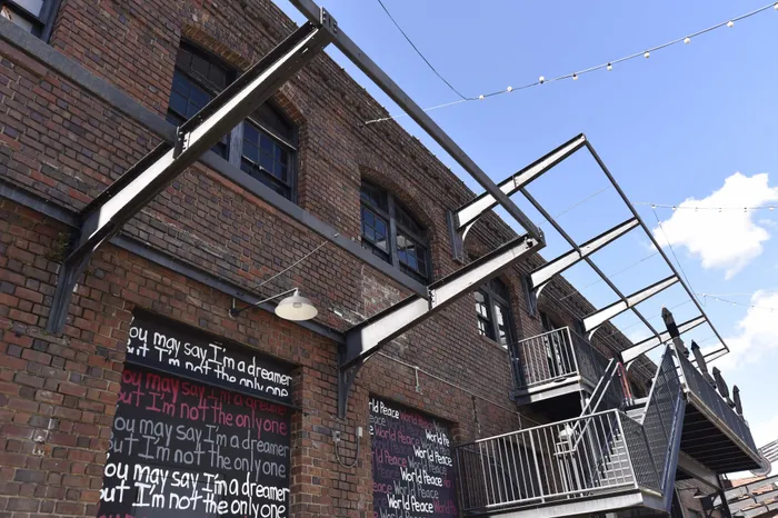 Charming urban loft building with rustic brick exterior, featuring inspirational wall art and modern steel staircases under a bright blue sky.