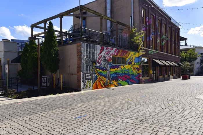 Vibrant urban scene with colorful street art mural on an industrial-style building, under a clear blue sky.