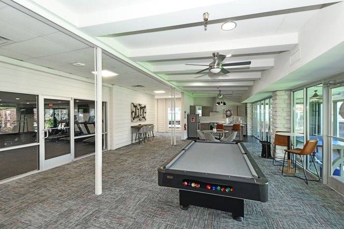 Modern recreational room featuring a sleek pool table, cozy seating area, and stylish kitchenette, perfect for entertaining and relaxation.