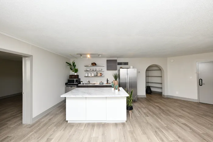 Modern open-concept kitchen with sleek marble island, stainless steel appliances, and elegant wood flooring.
