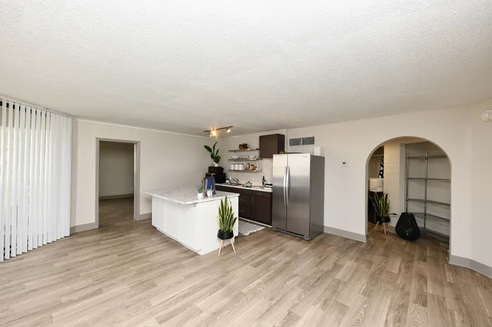 Modern kitchen design with sleek stainless steel appliances, elegant marble countertops, and open shelving, set against stylish wood flooring and spacious layout.