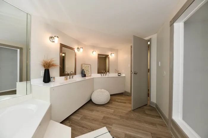 Elegant bathroom with a dual vanity, modern lighting, and chic wooden flooring for a luxurious feel.