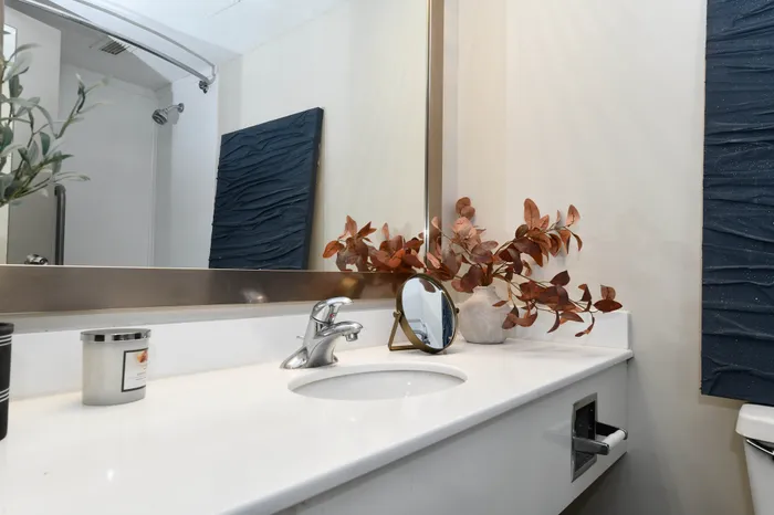 Elegant bathroom vanity with a modern sink, chic decor, and a large mirror enhancing natural light.