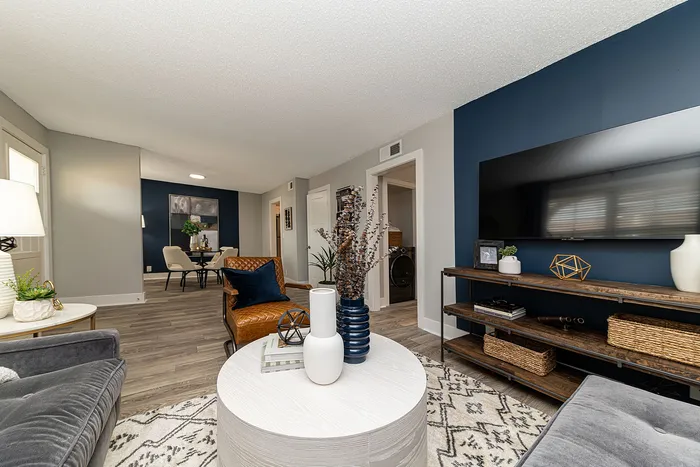 Elegant living room with contemporary decor, featuring plush seating, a sleek white coffee table, and a large wall-mounted TV, exuding a cozy yet modern atmosphere.