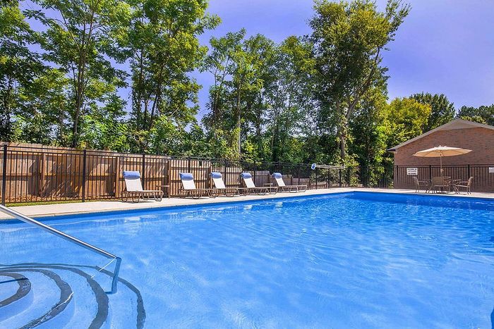 Charming outdoor pool area with crystal-clear water, surrounded by lush greenery and inviting lounge chairs for relaxation.