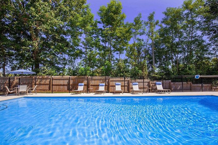 Inviting outdoor swimming pool surrounded by lush greenery and comfortable lounge chairs, perfect for relaxation and leisure.