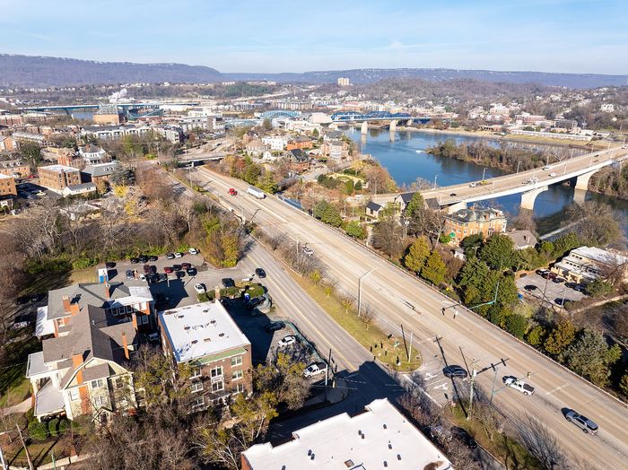 Scenic aerial view of a vibrant urban landscape along a river, featuring bridges, lush greenery, and charming residential buildings.