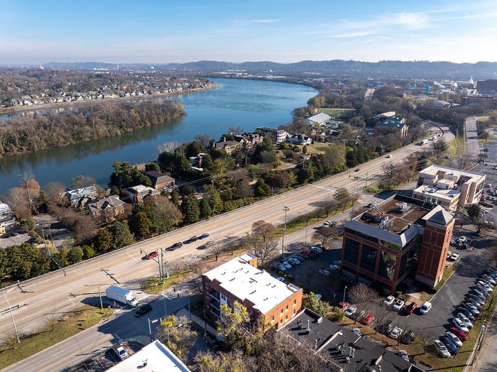 Stunning aerial view of a serene riverside neighborhood with lush greenery and modern architecture, offering a picturesque living environment.