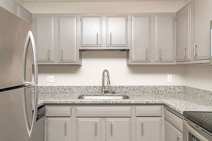 Modern kitchen with sleek stainless steel appliances, elegant granite countertops, and stylish gray cabinetry.