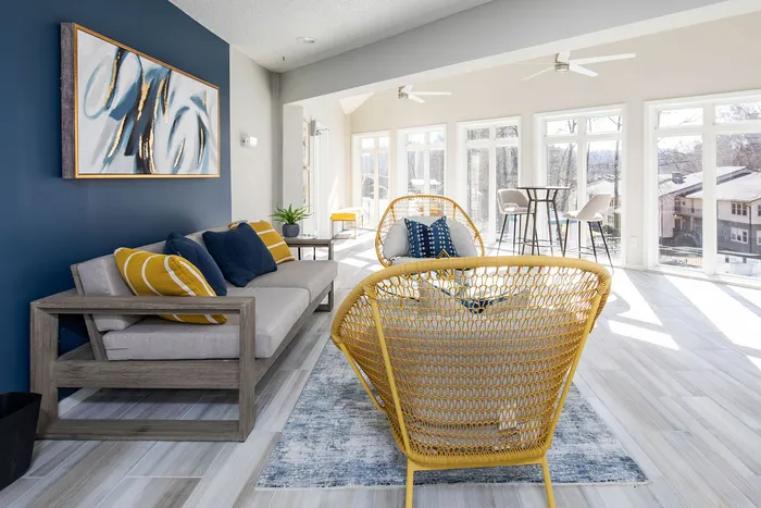 Bright and airy living room with modern decor, featuring stylish furniture, colorful cushions, and expansive windows overlooking a scenic view.