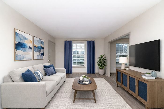 Inviting living room with elegant decor, featuring a comfy beige sofa, modern wooden coffee table, and stylish blue accents.