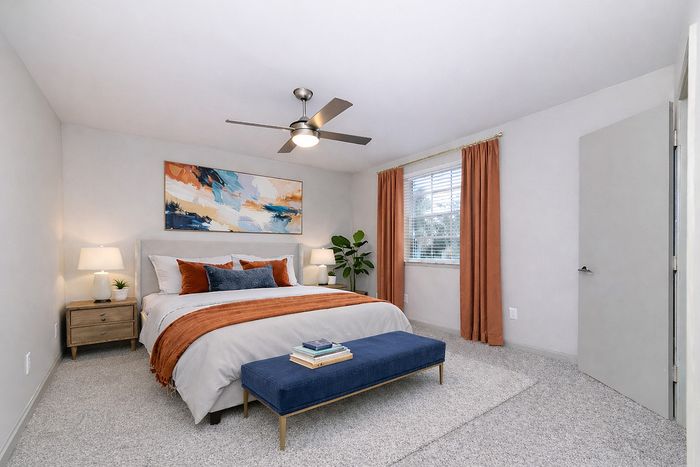 Elegant bedroom with a plush bed, vibrant artwork, and a sophisticated color palette of orange and blue accents.