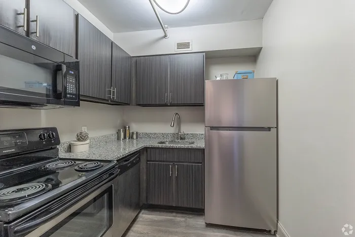 Modern kitchen with sleek dark cabinetry, stainless steel appliances, and elegant granite countertops.