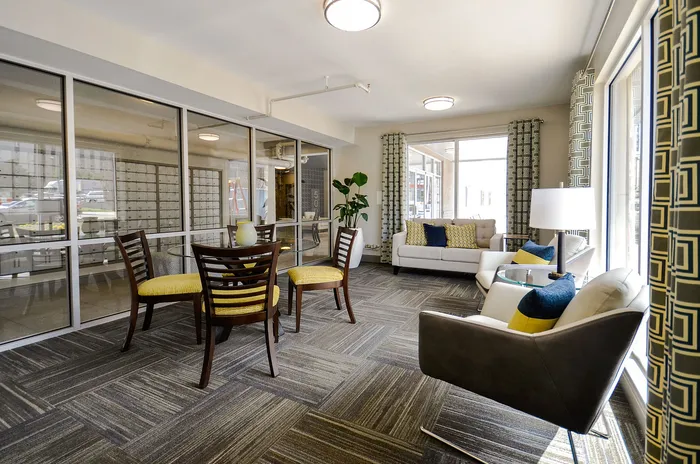 Inviting urban lounge area with contemporary furniture, bright accents, and floor-to-ceiling windows offering ample natural light.