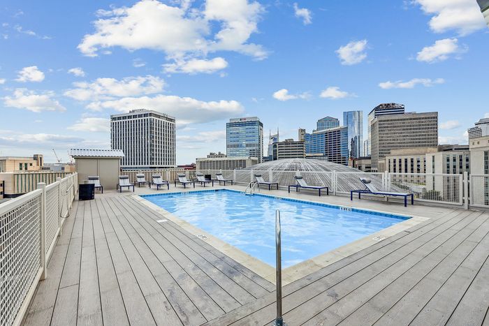Rooftop oasis featuring a sparkling swimming pool with stunning cityscape views and surrounding lounge chairs for relaxation.