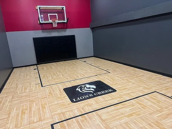 Modern indoor basketball court at Lion's Creek, featuring sleek wood flooring and vibrant wall accents.