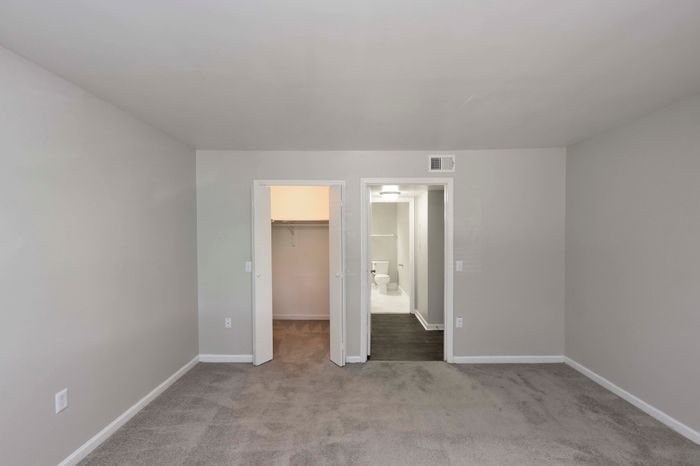 Bright, carpeted bedroom featuring a spacious walk-in closet and direct bathroom access, creating the perfect blend of comfort and convenience.
