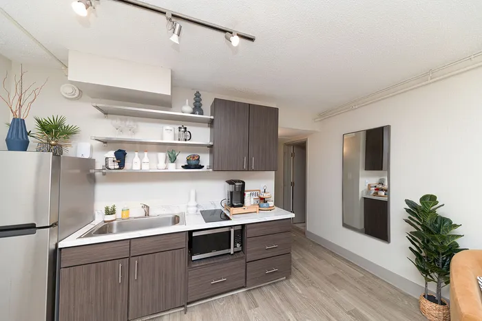 Contemporary kitchen with sleek wooden cabinets, open shelving, stainless steel appliances, and stylish decor.