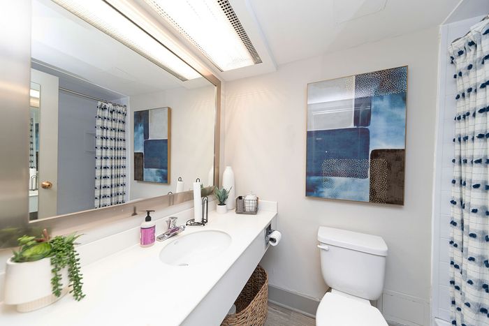 Modern bathroom with elegant white countertop, stylish blue abstract art, and chic decor accents.